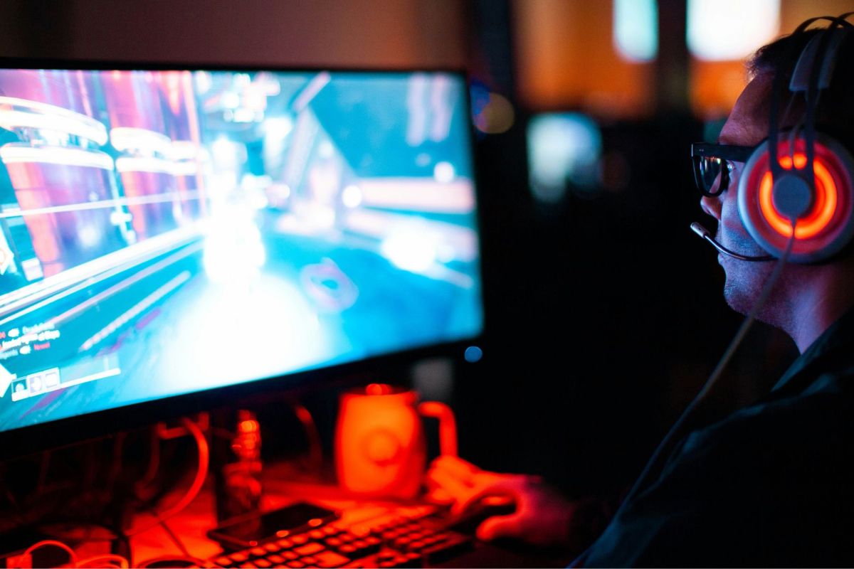 person wearing glasses and bright headphones playing a computer game