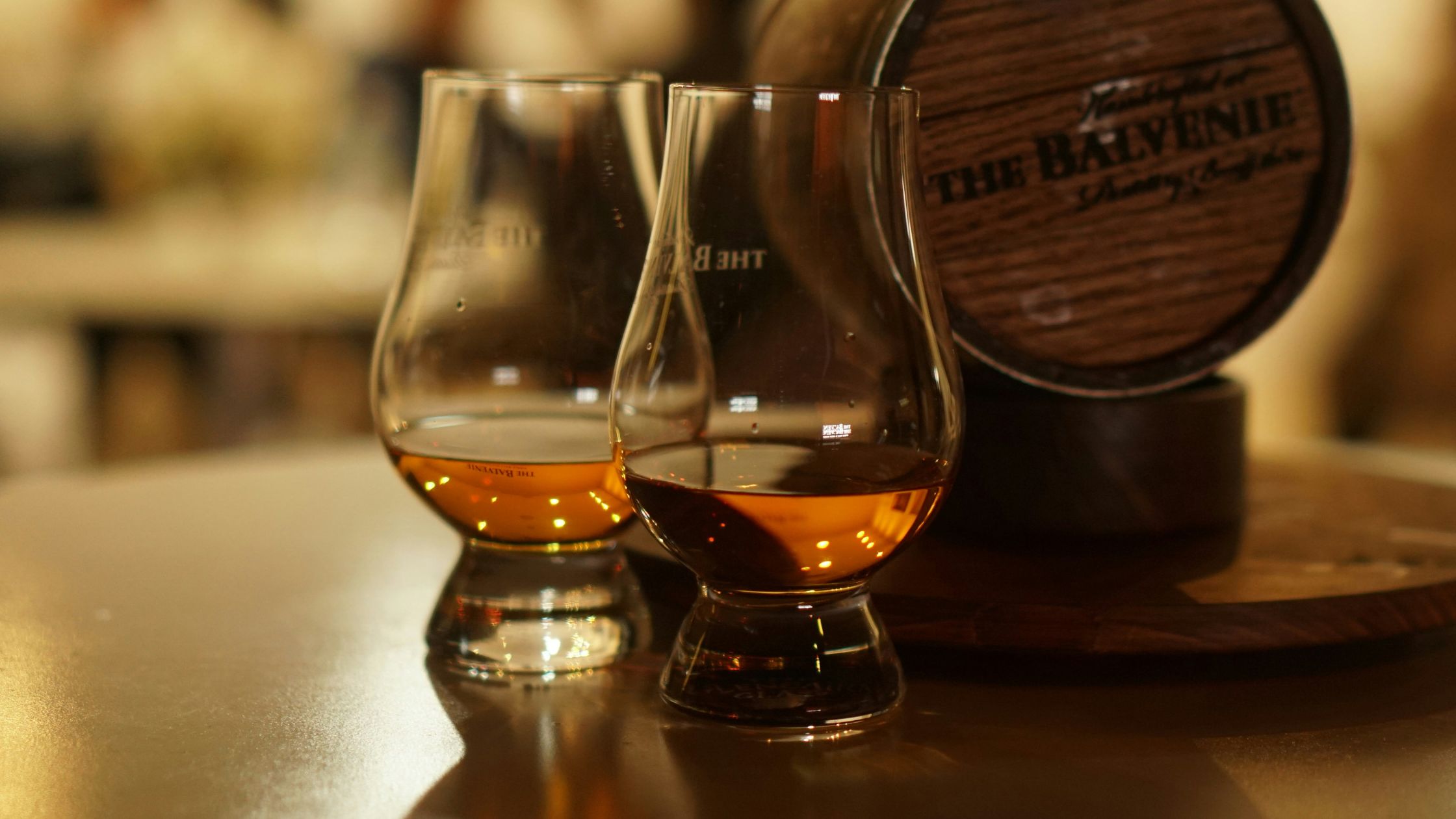Two Glencairns of whiskey next to a The Belvenie barrel