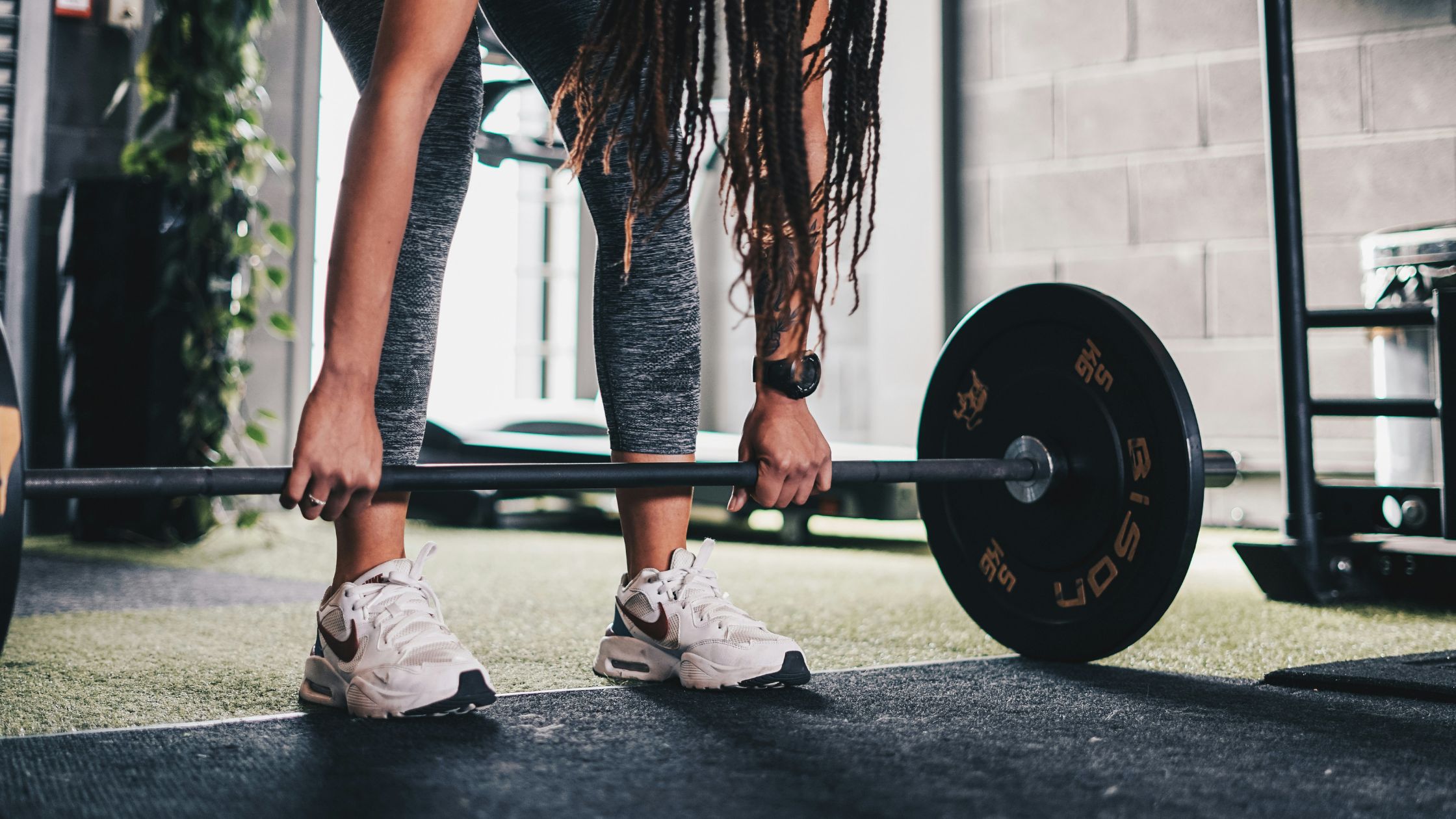 woman holding barbell with plates loaded while wearing fitness watch